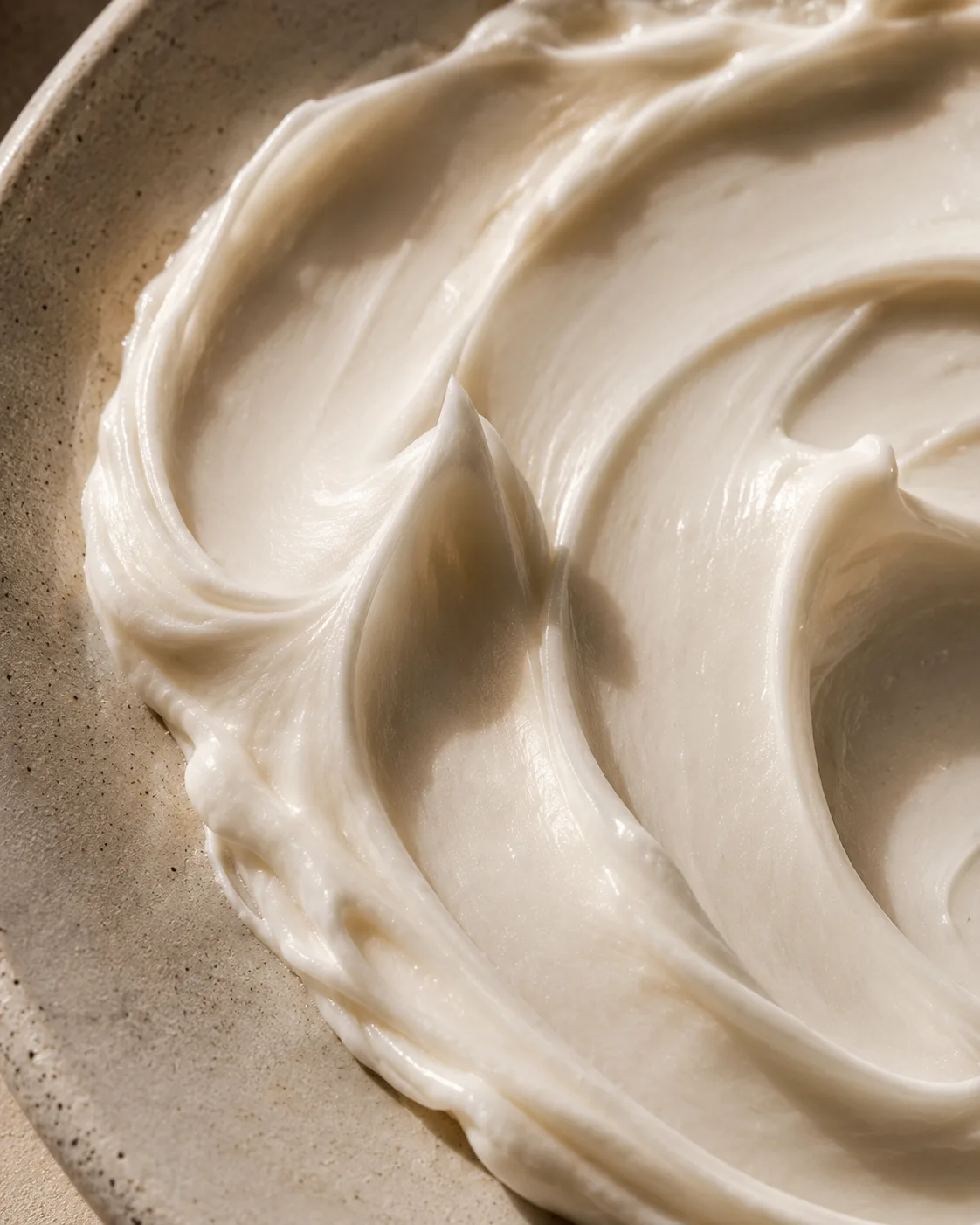 Macro detail of whipped cream texture swirled in a ceramic dish